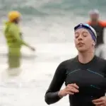 Triathlete finishing swim leg during training session, representing how many hours should triathletes train each week