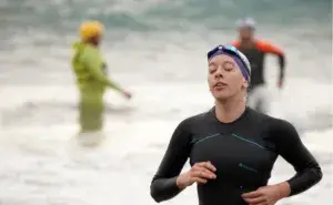 Triathlete finishing swim leg during training session, representing how many hours should triathletes train each week