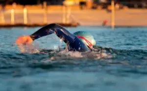 triathlete swimming in open water showing how often should you train for a triathlon