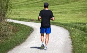 Man running on a gravel path while training how to get better at running long distance