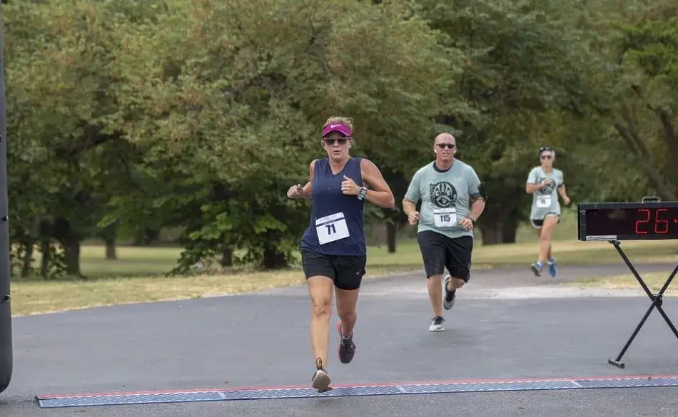 Runner crossing finish line demonstrating how to run faster without increasing your mileage