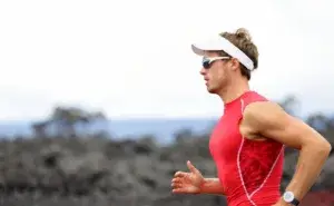 Ironman triathlon running athlete wearing red tri suit on the marathon course