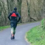 Runner practicing run walk ratio chart training on a quiet forest path