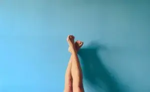 Person resting with legs elevated against a wall to reduce swollen legs after running