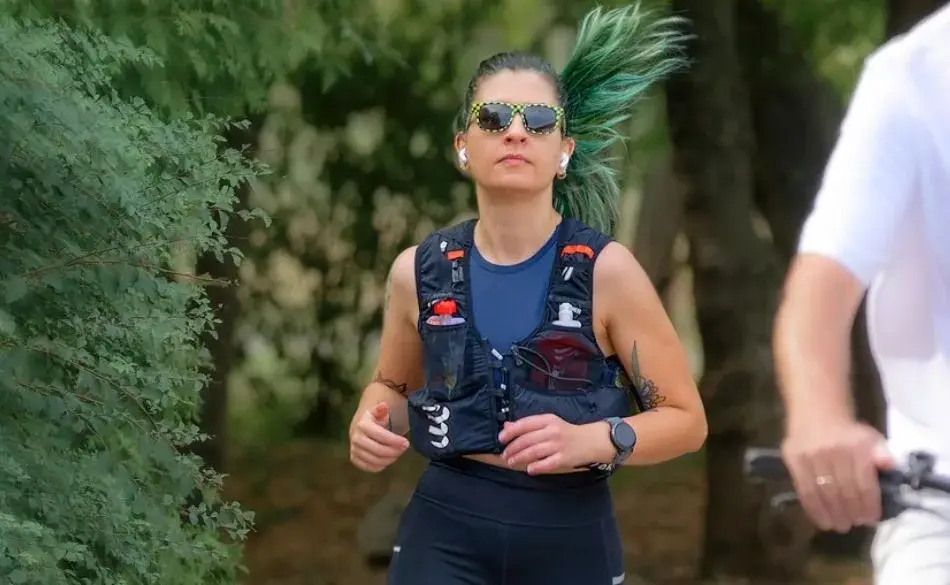 Runner jogging outdoors wearing earbuds to show how music can make you run faster