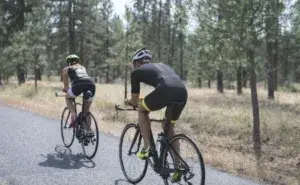 Cyclists training on a quiet forest road during an Ironman 70.3 preparation period, showing how long it takes to train for an Ironman 70.3