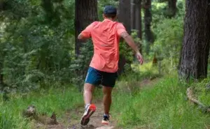 Runner training on a forest trail, showing consistent running frequency and easy aerobic effort for long term endurance development