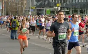 Runners racing through a city street during the Melbourne half marathon event with race bibs and crowd support