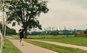 Runner on a parkrun course through a park with city skyline in the background