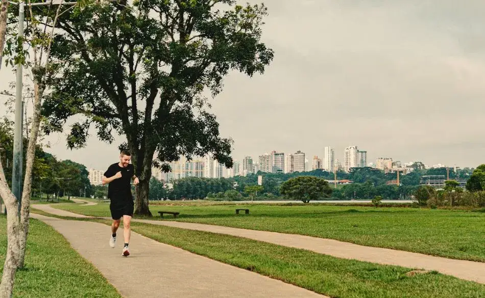 Runner on a parkrun course through a park with city skyline in the background