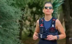 Woman running on a park path wearing a hydration vest during a training run for weight loss