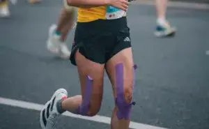 Runner with kinesiology tape on both knees racing on a road during a running event