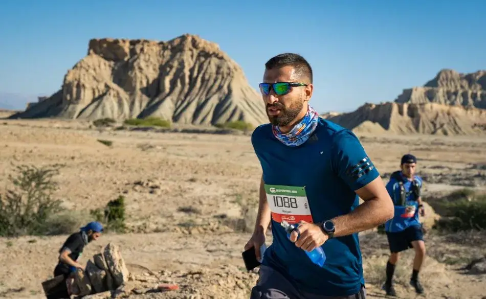Ultra marathon runner on a rocky desert trail carrying a water bottle during a trail race