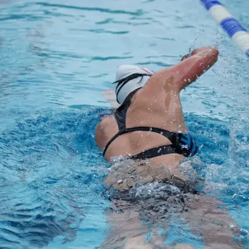 Swimmer performing freestyle stroke during intense training session, illustrating do you sweat when you swim.