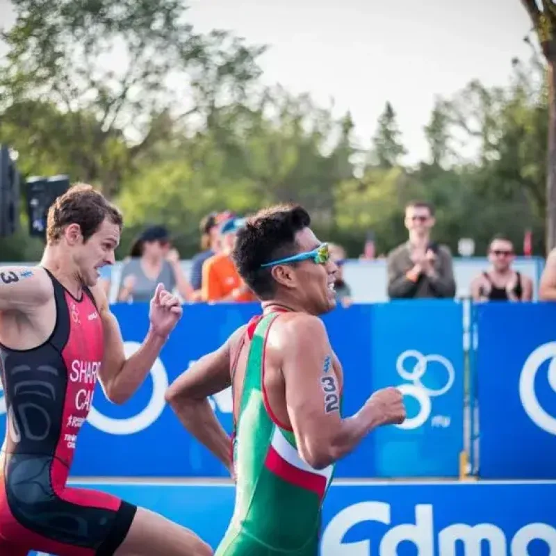 Two triathletes sprinting to the finish line during a triathlon, showcasing the competitive spirit of Perth triathlon coaching.